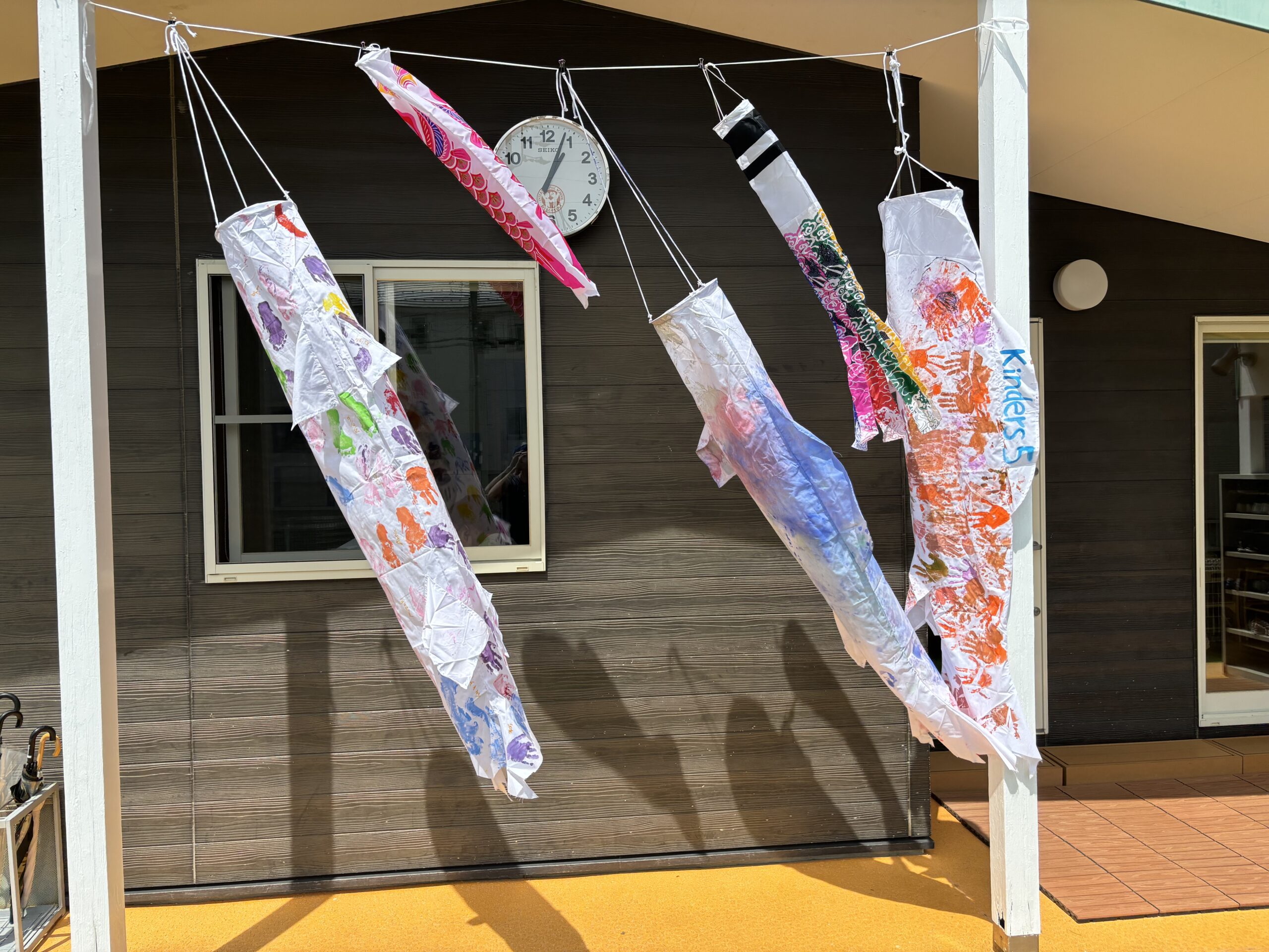 子どもの日 鯉のぼりアート|ディスカバリーインターナショナルスクール 名古屋のディスカバリーインターナショナルスクールで子どもたちが制作した鯉のぼりが子どもの日に校舎の前に飾られています。国際的な幼稚園ならではの文化的学びと季節の行事を楽しむ様子です。