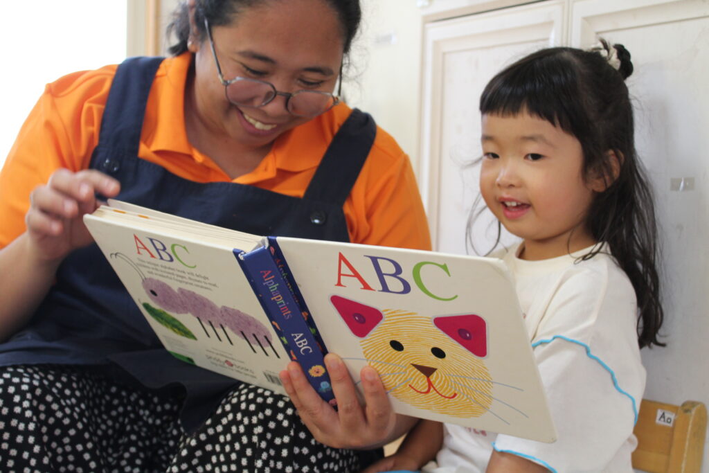 teacher reading to child Teacher reading a picture book with a preschool child at Discovery International School